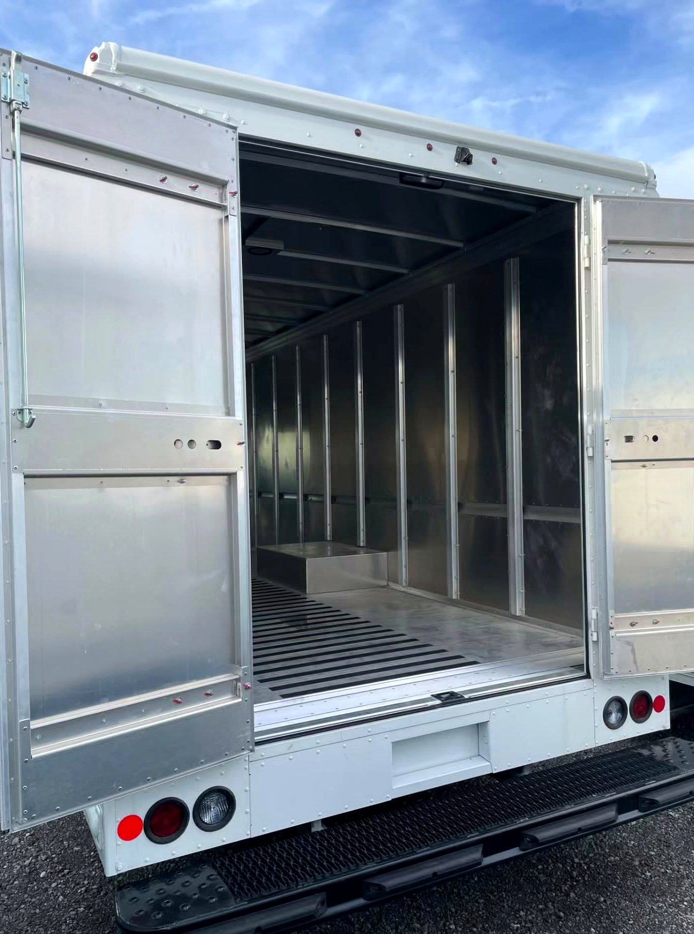 Empty aluminum food truck shell with rear doors open